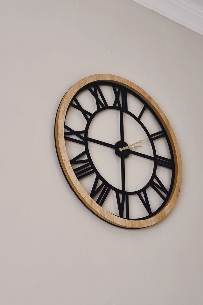 Decorative wall clock featuring Roman numerals with a wooden frame.